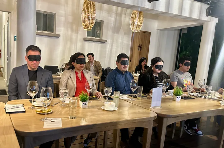 Fila de invitados con antifaces en una mesa durante una experiencia de cata a ciegas