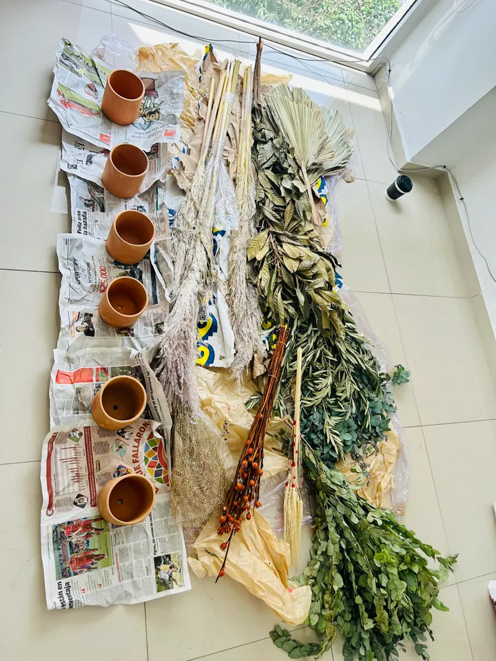 Macetas de barro, hojas de palma secas, pampa y eucalipto dispuestos para un taller floral