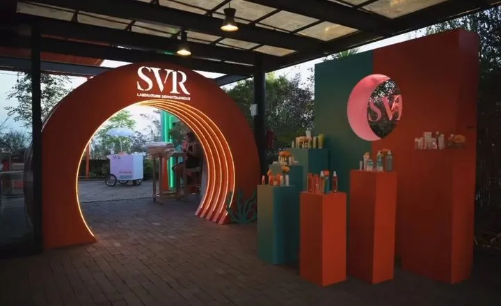 SVR skincare brand activation with an illuminated orange tunnel archway and product plinths at dusk