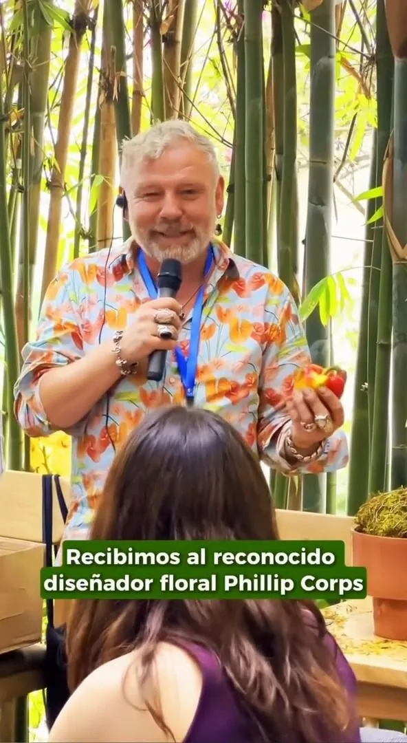 El diseñador floral Phillip Corps hablando por micrófono en un evento entre bambú y vegetación
