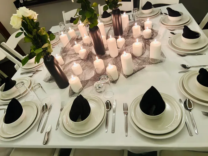 Mesa de cena a la luz de las velas en blanco y negro, con centros de rosas y numerosas velas