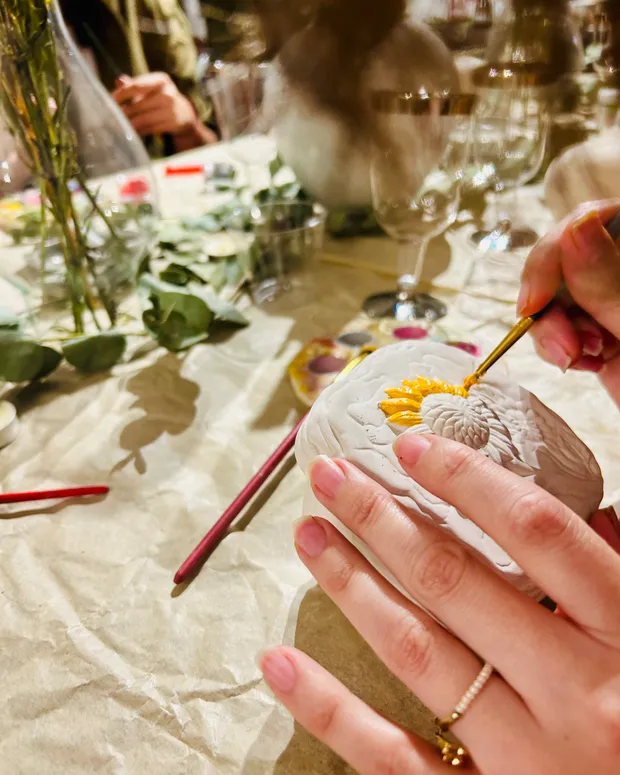 Hand painting a sunflower onto a stone at a creative table workshop
