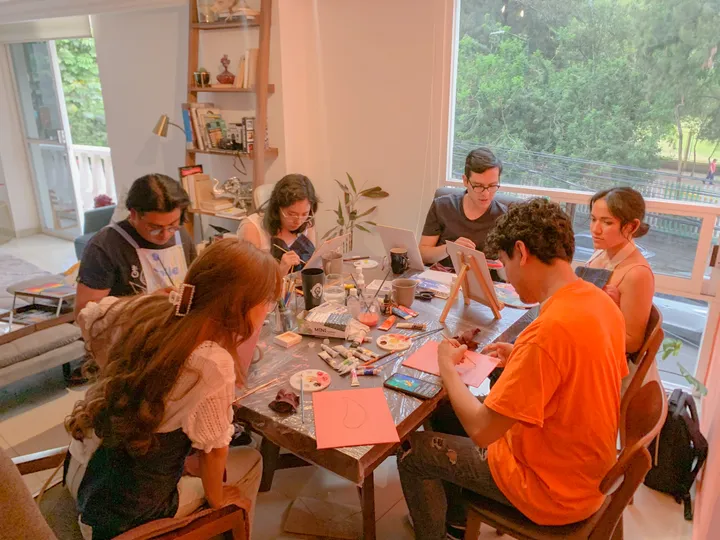 Grupo concentrado en un taller de manualidades en papel junto a grandes ventanales soleados