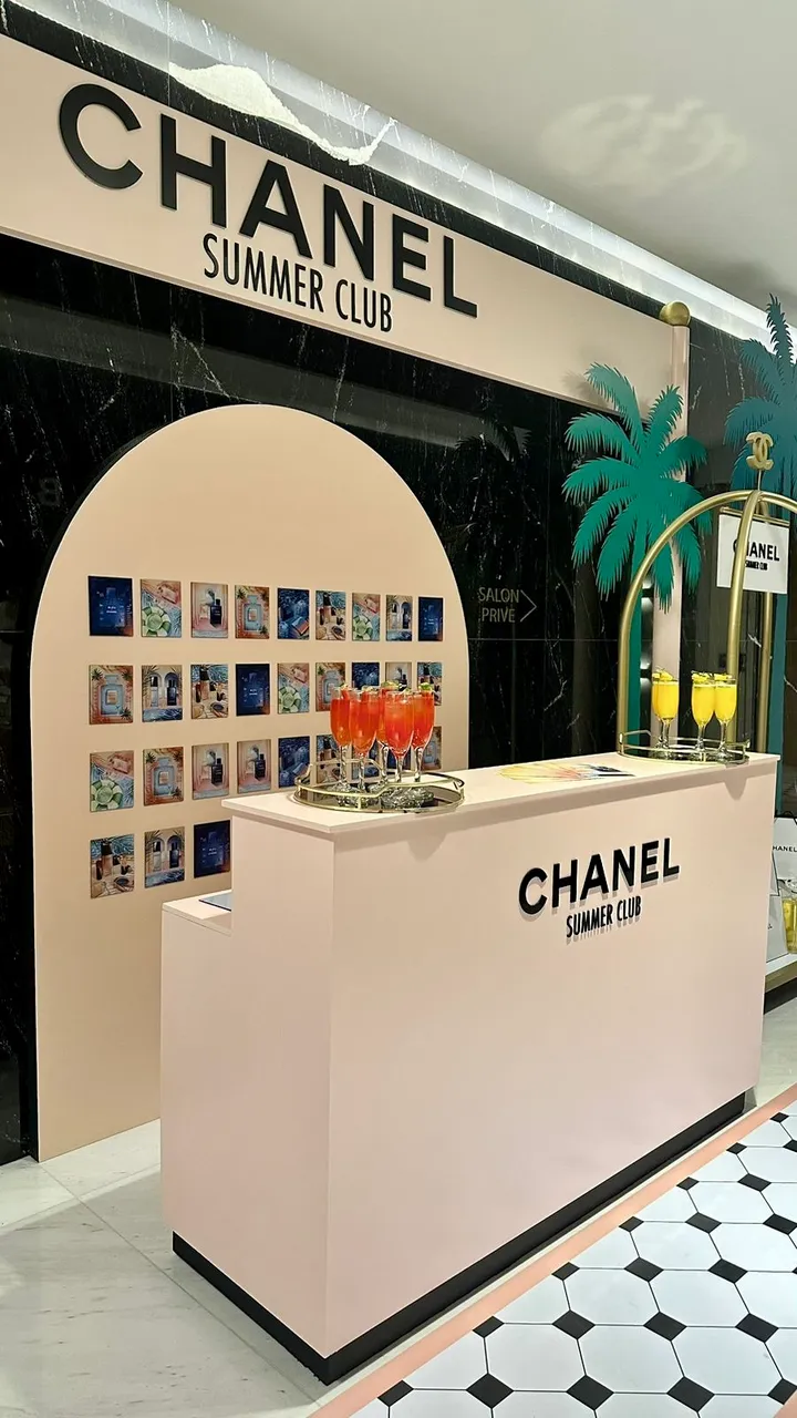 Chanel Summer Club branded pop-up bar with an archway, a wall of colourful prints and orange welcome cocktails